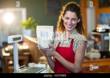 Sorridente personale femminile in possesso di una voce di generi alimentari a contatore a pagamento Foto Stock
