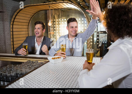 Amici dando alta cinque mentre guardi la TV Foto Stock