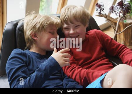 Angolo di alta vista di felice fratelli seduti su una sedia a casa Foto Stock