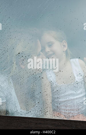 Amorevole Madre e figlia visto attraverso il vetro della finestra Foto Stock