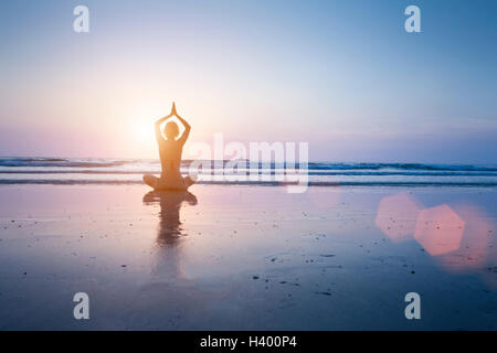 Donna felice godendo di una sana pratica dello yoga al sorgere del sole su una bella spiaggia di sabbia di Koh Chang, Thailandia Foto Stock