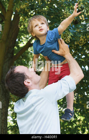 Basso angolo di visione del padre figlio di sollevamento contro tree Foto Stock