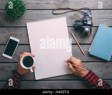 Immagine ritagliata dell uomo con tazza di caffè durante la scrittura su carta a tavola Foto Stock