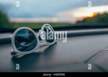 Close-up di occhiali da sole sul cruscotto di automobile contro il parabrezza Foto Stock