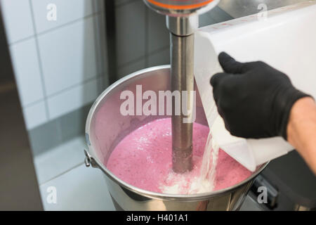 Dettaglio dell'uomo ingrediente di miscelazione in gelato alla fragola in macchina Foto Stock