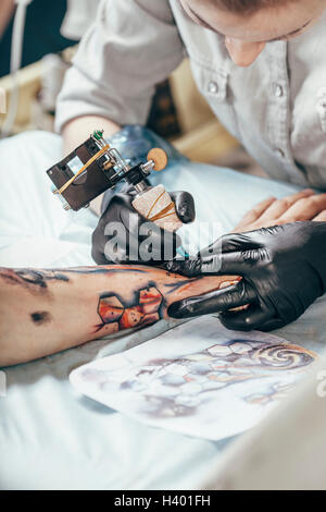 Artista concentrato tatuaggio disegno sulla mano umana Foto Stock