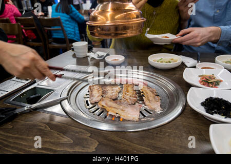 La cottura della carne sul grill da tavolo in un Barbecue Coreano ristorante, Seoul, Corea Foto Stock
