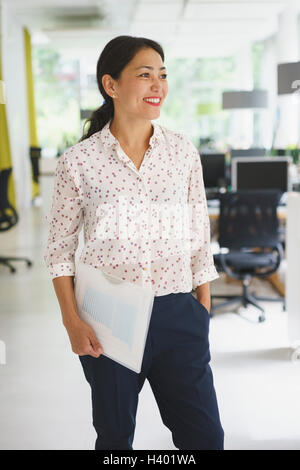 Fiducioso imprenditrice azienda file mentre in piedi presso il creative office Foto Stock