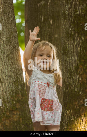 Ritratto di Allegro ragazza gesticolando stando in piedi in mezzo di alberi in posizione di parcheggio Foto Stock