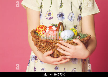 Pasqua, ragazze, Pasqua nido, detiene, close up, festa di Pasqua, tempo di Pasqua, bambino, 8 anni, infanzia, Flechtkorb, basket, uova di Pasqua, dai colori vivaci e luminosi, vernici, sorpresa, presente, Pasqua presente, orgoglio, sfondo rosso Foto Stock