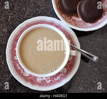 Caffè con latte e biscotti al cioccolato in una bella bone china cup Foto Stock