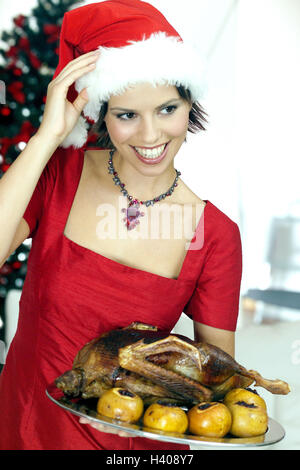 Natale, donna, giovane, Santa's hat, oca arrosto, metà ritratto, salotto, la vigilia di Natale, feste, festa di Natale, arrosti, roast, serve, hostess, rivestimento, cappuccio, donna di Natale, abito, festively, felice, sorriso, allegria, gioia Foto Stock