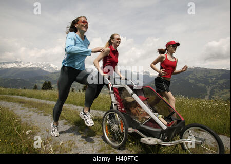 Vicolo del paese, donne, ragazze, sportily, jog, spingere pareggiatore baby, giovani amici, filiale, neonati, carrozzine, sport, sportivi, jogging, in funzione, funzionante, la perseveranza, la perseveranza sport, stamina formazione, formazione, allenamento fitness abbigliamento sportivo Foto Stock