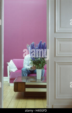 Sale di soggiorno, divano, uomo, siede, prenotate letture, tavolino, mazzo di fiori tempo libero, hobby, attività attività informali, decorazione, fiori, mazzo, vase, spazio abitativo, copre in interni, a casa Foto Stock