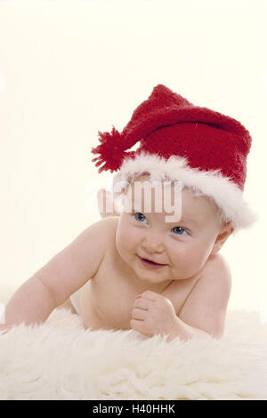 Baby, Santa's hat, ridere bambino, infantile, cappuccio, cappello di Natale rosso-bianco, pelle di agnello, giacciono, softy, comodamente, Natale, yule tide, X-mas, infanzia e innocenza, rivestimento, divertente, umorismo, Natale bambino, ironicamente, felice, studio Foto Stock