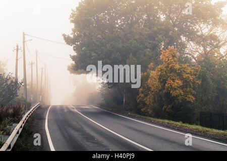 Vuoto autostrada rurale in autunno mattinata nebbiosa, foto stilizzata con calde tonalità effetto, vecchio stile instagram filtro Foto Stock