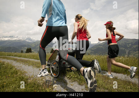 Vicolo del paese, donne, ragazze, sportily, jog, spingere pareggiatore baby, vista posteriore, giovani amici, filiale, neonati, carrozzine, sport, sportivi, jogging, in funzione, funzionante, la perseveranza, la perseveranza sport, stamina formazione, formazione, fitness training, spor Foto Stock