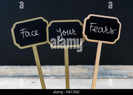 Messaggio motivazionale affrontare le tue paure scritto con un gessetto su legno mini etichette di Blackboard Foto Stock