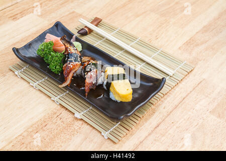 Il cibo giapponese Sushi Unagi e uovo dolci Sushi in piastra nera su un tavolo di legno. Foto Stock