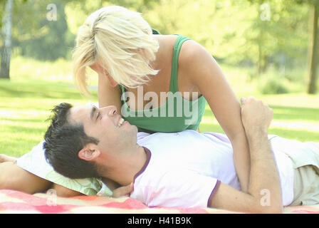 Giovane, prato, giacciono, estati, tappi, felice, donna bionda, uomo dai capelli scuri, 20-30 anni, giovani, ridere, riposo, take it easy, attesa, Nestle, giro, sentimento, di sicurezza, di vicinanza, di tenerezza, affettuosamente, all'esterno, tempo libero, parco, felice, cade nell'amore, amore, solidarietà, contatto visivo, sorriso, week-end, colore umore, colore verde, pic-nic Foto Stock