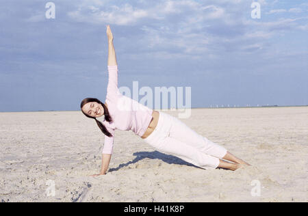 Spiaggia, donna, giovane, per il tempo libero, i piedi nudi, la pratica dello yoga, 20-30 anni, 20 anni, dai capelli scuri, giacciono, braccio di supporto, piedi, stretch, yoga e meditazione, di riposo e di svago, di riposo e di relax, equalizzatore, concentrazione, la sensazione del corpo, energia, fitness e wellness, salute, wel Foto Stock