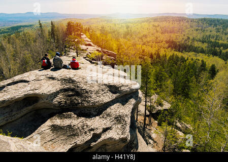 Amici caucasici seduto sulla roccia di montagna ammirando vista panoramica Foto Stock