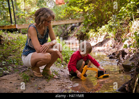 Madre caucasica guardando figlio giocare con giocattoli da costruzione in fiume Foto Stock