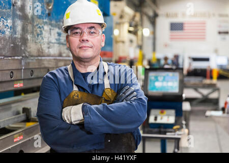 Grave operaio ispanico che pongono in fabbrica Foto Stock