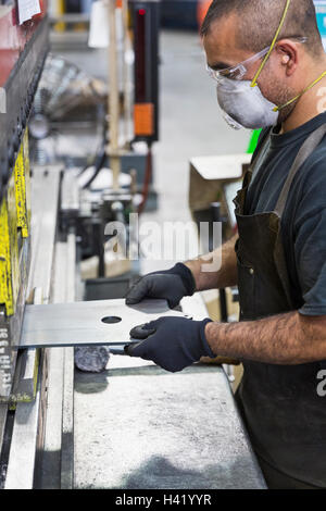 Ispanico Lavoratore che indossa la maschera di metallo Fabbricazione in fabbrica Foto Stock