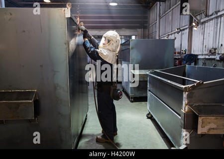 Lavoratore caucasica macinazione di contenitore metallico in fabbrica Foto Stock
