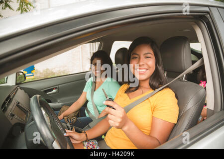 Ispanica sorridente madre e figlia in posa in auto Foto Stock