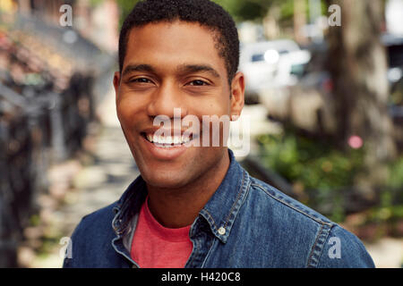 Uomo sorridente in posa sul marciapiede della città Foto Stock