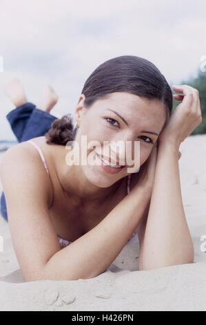 Spiaggia, donna, per il tempo libero, giacciono, sabbia, ricreazione, 20-30 anni, 23 anni, giovani, jeans, top visualizza fotocamera, sorriso, godetevi, felice, corso, naturalezza, equilibrio, soddisfazione, riposo, take it easy, piacevole sensazione, di riposo e di vacanza, tempo libero Foto Stock