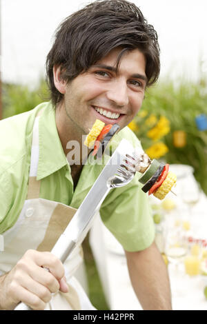 Giardino, uomo, grill liers, sorriso, tenere spiedo vegetali, ritratto, Foto Stock