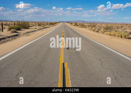 Strada stretta nel deserto occidentale conduce nelle montagne distanti. Foto Stock