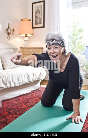 Senior donna, materassino yoga, inginocchiato, stretching, pugno, urlando,, Foto Stock