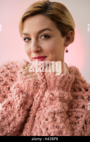 La donna caucasica snuggling in rosa maglione Foto Stock
