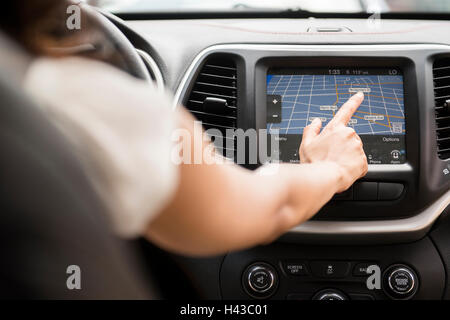 Razza mista donna usando il touch screen mappa di navigazione in auto Foto Stock