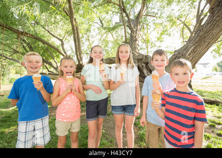 Caucasian i ragazzi e le ragazze a mangiare il gelato coni Foto Stock