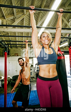 Razza mista l uomo e la donna pendenti da barre in palestra Foto Stock