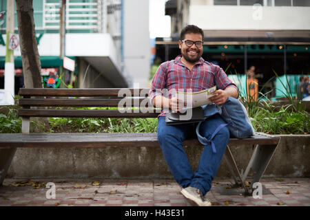 Ispanico uomo seduto su un banco di lavoro leggendo la brochure Foto Stock