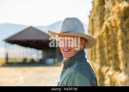 Sorridente Caucasian contadino vicino di pile di fieno Foto Stock