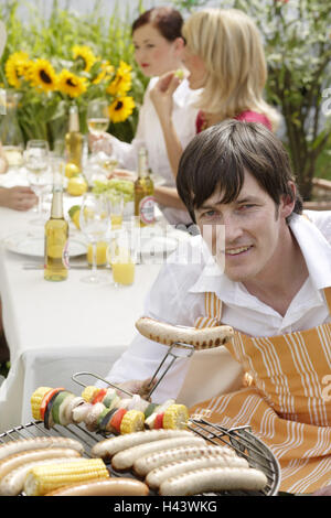 L'uomo, grill, piccole salsicce, grill liers, tenere, giardino, party, Foto Stock