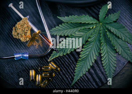 La marijuana medica prodotti tra cui la cannabis leaf, essiccato bud, frantumi pezzo, cbd caps e un hash di olio nero su uno sfondo di legno Foto Stock