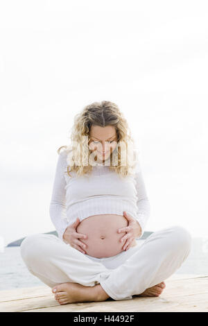 Donna, giovane, felice, in gravidanza, cross gambe, toccare, addome, bridge, mare, modello rilasciato, Foto Stock