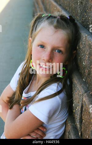 Contemporanea o moderna ritratto di una giovane ragazza carina appoggiato su di un muro di mattoni sorridente Foto Stock