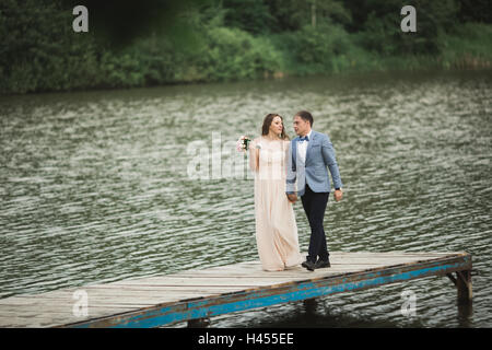 Elegante lo sposo con il suo felice Gorgeous Brunette sposa sullo sfondo di un lago Foto Stock