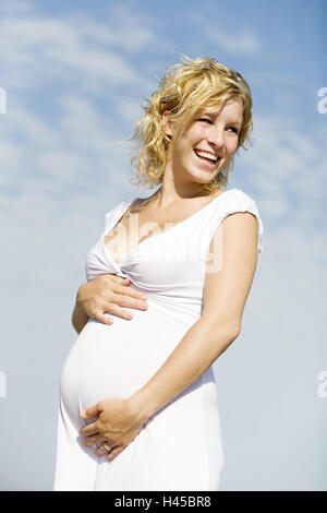 Donna incinta, in piedi, felice, ridere, esterni Foto Stock