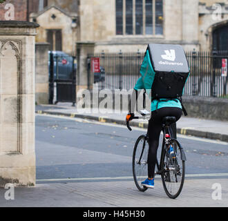 Un ciclista deliveroo dal sempre più popolare il cibo caldo e fast food società di consegna in bicicletta attraverso strade di città. Foto Stock