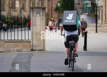 Un ciclista deliveroo dal sempre più popolare il cibo caldo e fast food società di consegna in bicicletta attraverso strade di città. Foto Stock